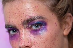 Paint splash, metallic gold and irridescent purple and pink tones on model Mia's makeup