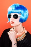 Blue hair, sunglasses, orange lips and orange background.  Editorial makeup.