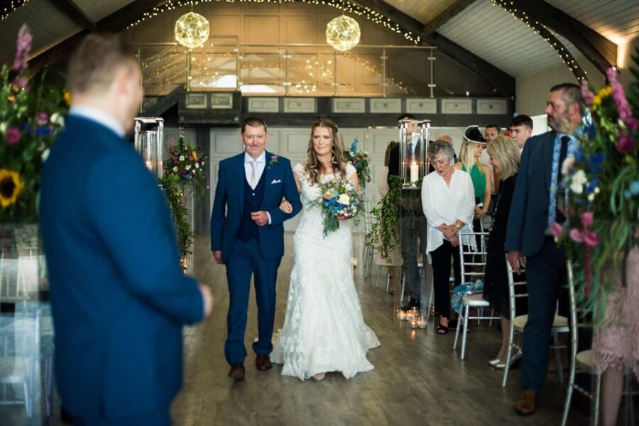 Bride Sally's skin is glowing as she walks down the aisle at Yorkshire Wedding Barn near Richmond